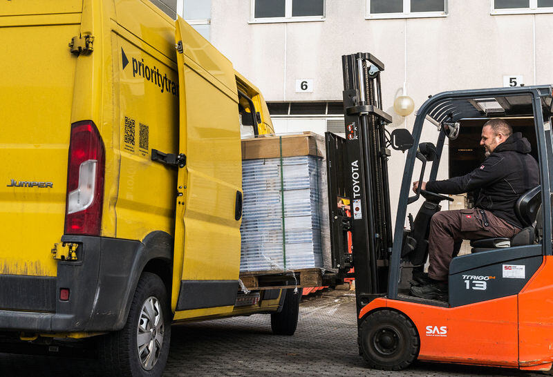 Trabajador cargando paquetes en una furgoneta amarilla con un montacargas, Asendia