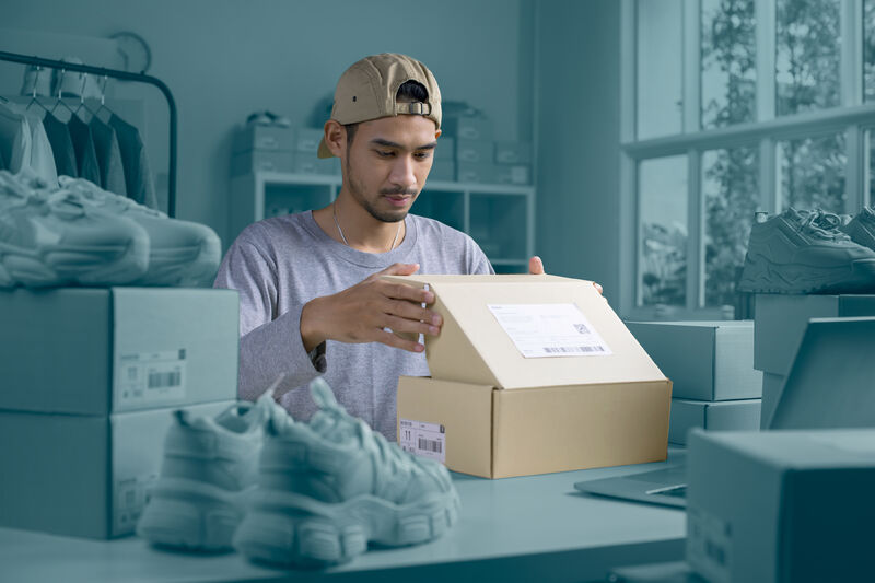 Hombre preparando paquete en tienda, soluciones para pequeñas empresas - Asendia