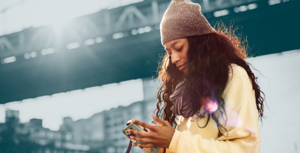 Mujer joven usando su teléfono móvil, simbolizando el alcance global del e-commerce.